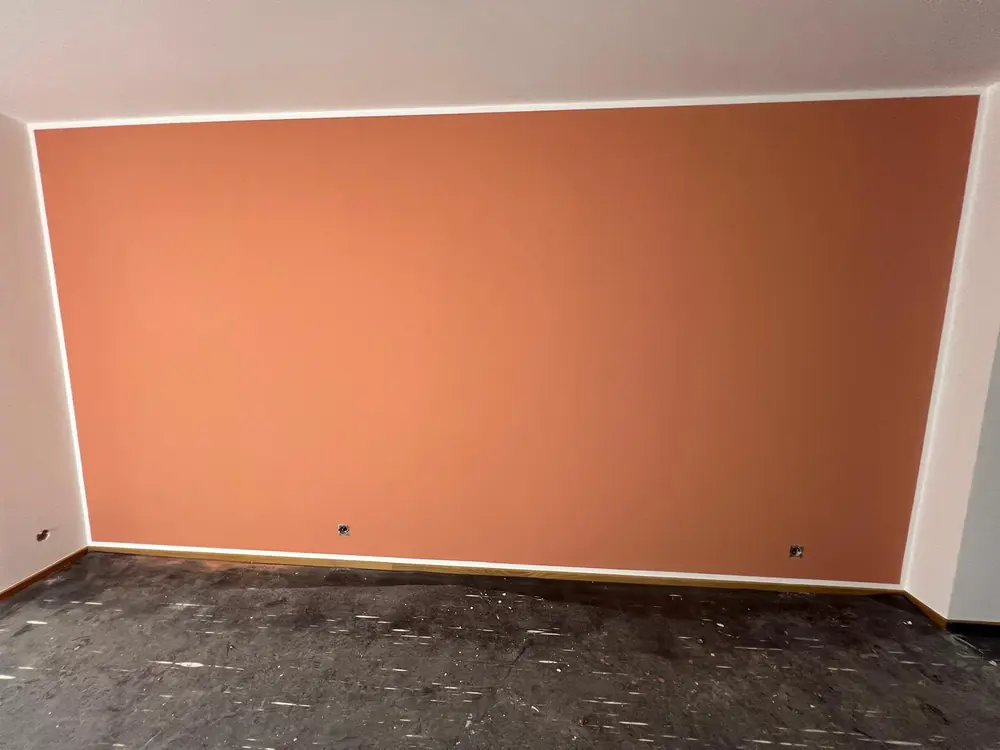 Akzentwand in Terrakotta, frisch gestrichen, mit sauberer Kante zur weißen Decke