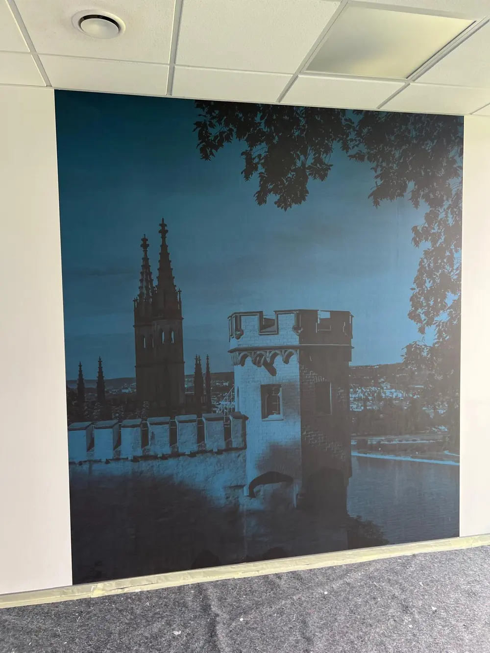 Fototapete in Blautönen mit Burgmotiv an einer Bürowand