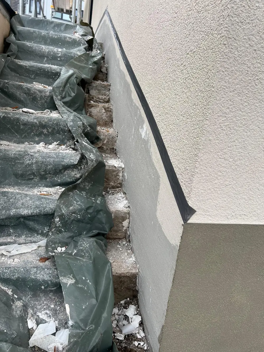 Treppenhaus mit neu verputzten Wänden, Stufen mit Folie geschützt